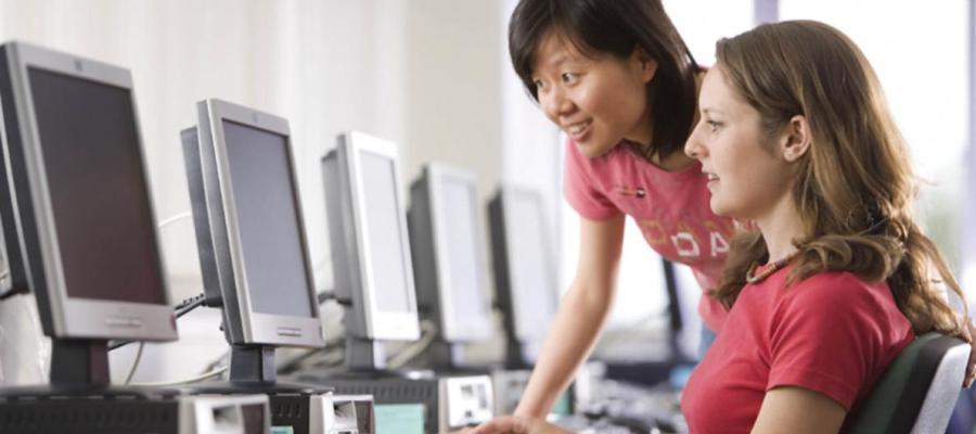 A woman helping another woman at a computer